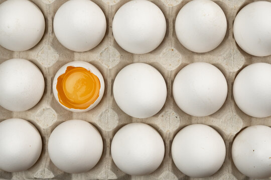 Cardboard tray with egg yolk and white eggs. Close-up.