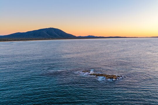 Aerial view of Diamond Head Beach and headland surrounded by ocean and coastal landscape beneath soft pastel morning light at Diamond Head.