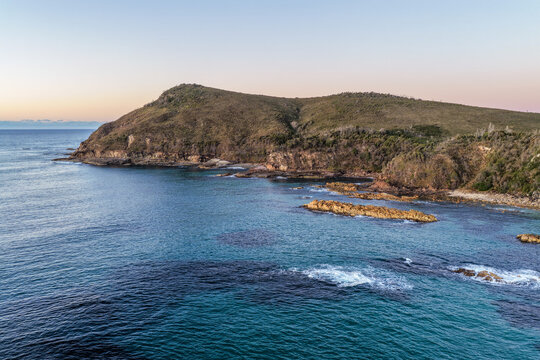 Aerial view of Diamond Head Beach and headland surrounded by ocean and coastal landscape beneath soft pastel morning light at Diamond Head.