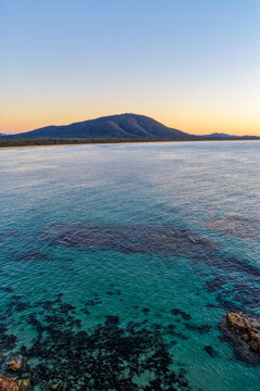 Aerial view of Diamond Head Beach and headland surrounded by ocean and coastal landscape beneath soft pastel morning light at Diamond Head.