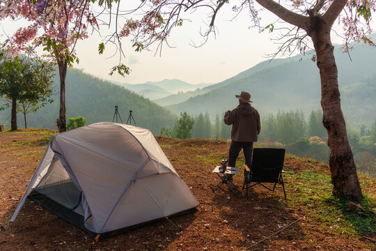 Male camper at camping tent enjoying with foggy mountain valley view in morning countryside