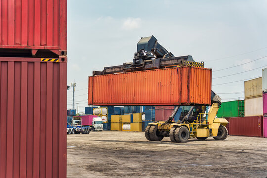 Reach stacker lifting shipping container in freight yard terminal logistics distribution depot