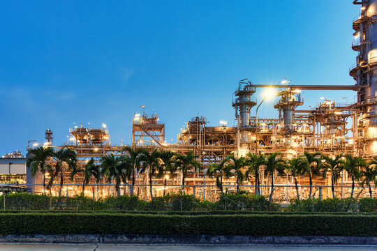 Oil Refinery Plant Illuminated with Glowing Lights and Distillation Column Pipe and Industrial Towers