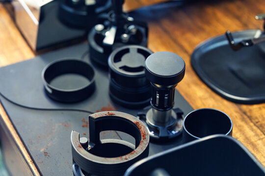 Professional espresso coffee tampering tools and accessories on wooden counter in cafe bar