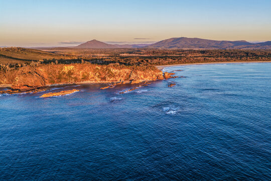 Aerial view of Diamond Head Beach and headland surrounded by ocean and coastal landscape beneath soft pastel morning light at Diamond Head.