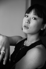 Profile portrait of a young Chinese woman, looking at camera. Black and white image. © Corina