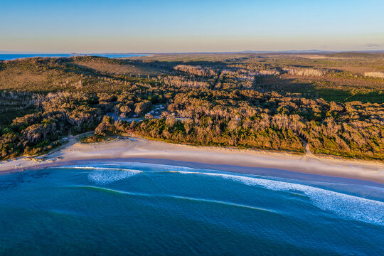 Aerial view of Diamond Head Campground beside the sandy beach and Pacific Ocean, surrounded by native coastal vegetation and natural landscape in Crowdy Bay National Park on the Mid North Coast