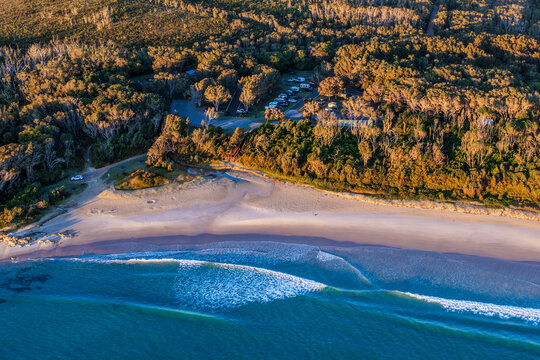 Aerial view of Diamond Head Campground beside the sandy beach and Pacific Ocean, surrounded by native coastal vegetation and natural landscape in Crowdy Bay National Park on the Mid North Coast 