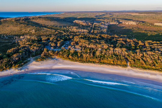 Aerial view of Diamond Head Campground beside the sandy beach and Pacific Ocean, surrounded by native coastal vegetation and natural landscape in Crowdy Bay National Park on the Mid North Coast 