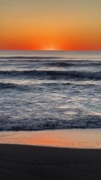 Beautiful sunset over the sea o ocean waves with an orange sky.