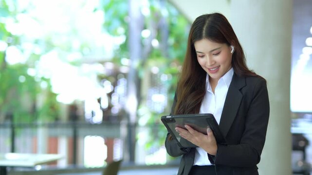 Elegant businesswoman in suit using digital tablet outside office
