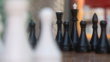 Black Chess Pieces on Outdoor Board with Blurred Foreground © Kasya