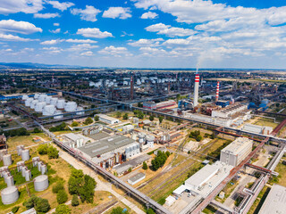 Fototapeta premium Industrial area with factories and storage tanks in clear weather showing transport routes and infrastructure