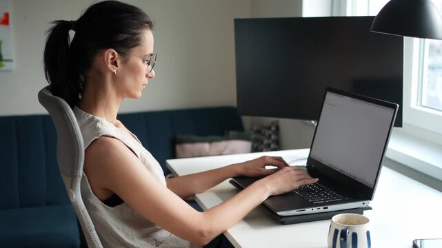 Side view of woman working on laptop from home office