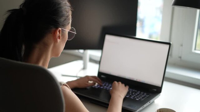 Rear side view of businesswoman working on a laptop