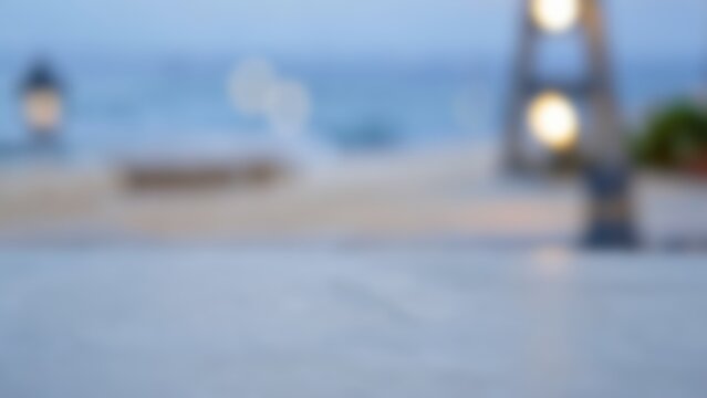 blurred coastal terrace evening background with warm bokeh lights and empty grey concrete surface for luxury summer product display mockups and lifestyle presentations