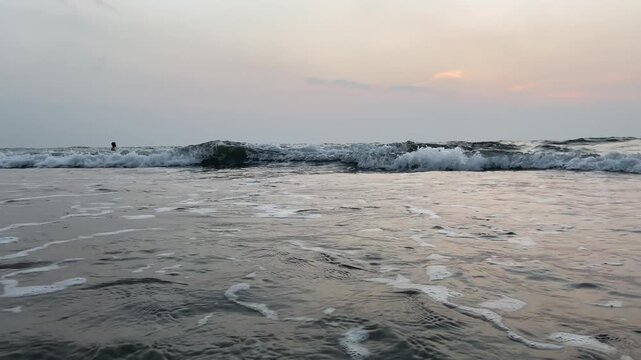 Pastel sunset sky over Goa beach with gentle surf and reflective wet sand, Indian coast evening vertical 4K B-roll