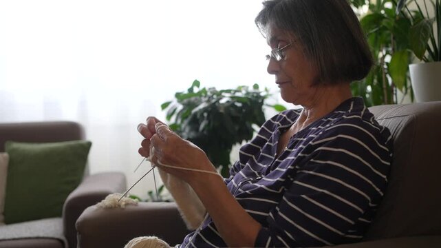 Side view of senior woman knitting at home