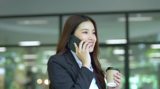 Close-up of Asian businesswoman using mobile phone, texting and cheating on her smartphone while outside office.