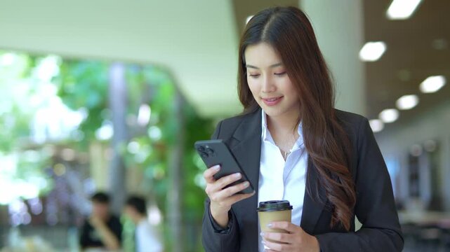 Close-up of Asian businesswoman using mobile phone, texting and cheating on her smartphone while outside office.