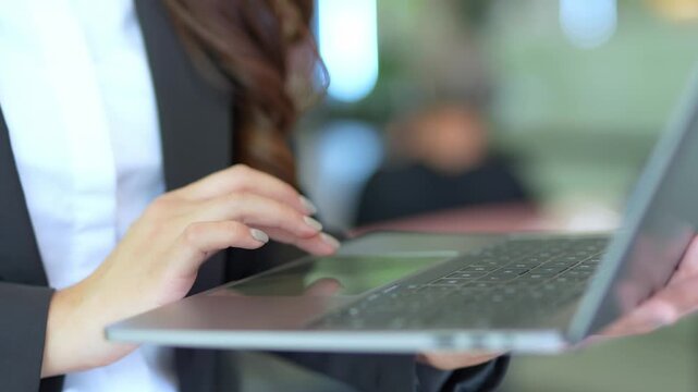 Close-up of Asian businesswoman using mobile phone, texting and cheating on her smartphone while outside office.