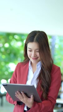 Elegant businesswoman in suit using digital tablet outside office