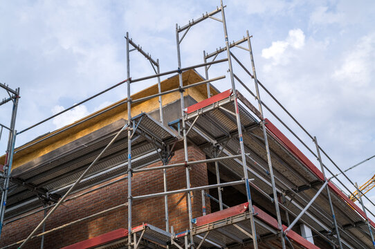Construction work on a building with scaffolding set up during the day under a cloudy sky