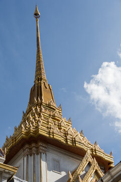 Golden Temple Spire and Ornate Roof Against Blue Sky at Wat Traimit Bangkok Thailand