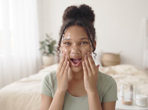 Young woman applying a facial scrub for skincare and beauty