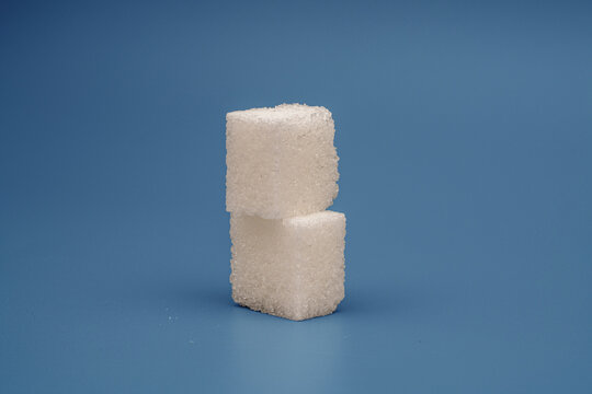 Two sugar cubes stacked on a blue background in a simple arrangement