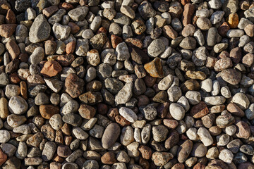 Closeup of scattered natural pebbles and gravel stones, featuring varied brown and grey tones for architectural or landscape textures © Olga Yashnikova