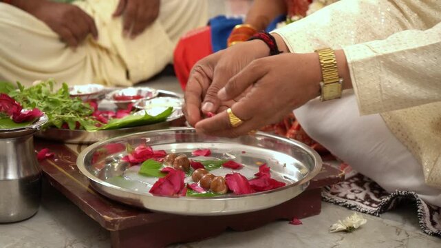 close up of  hand worshiping during pooja & offering flowers and rose petals