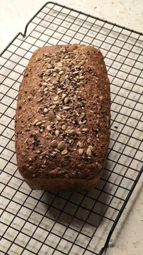Homemade low carb keto seeded bread cools on a wire rack, healthy baking, ketogenic food, fresh loaf, high fiber recipe.