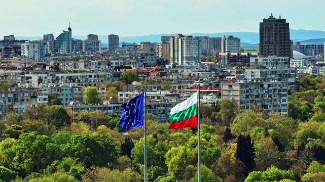 Waving Bulgarian national flag European Union EU flag poles Burgas city background aerial drone view park trees buildings cityscape travel destination Bulgaria
