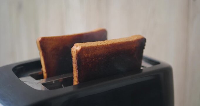 Smoke rising from burnt toast in toaster during breakfast preparation. Vertical video captures kitchen accident, cooking error, fire hazard, household safety concerns and everyday domestic life.