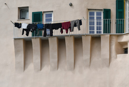 Hanging laundry on a clothesline over a long historic balcony with architectural machicolations and corbels in Camogli, Liguria, Italy