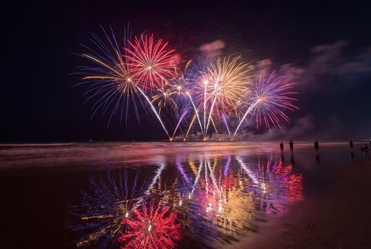 Colorful fireworks exploding over dark ocean beach at night celebration