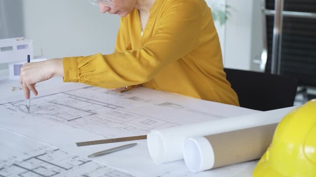 Architect hand drawing blueprints with compass tool, designing floor plans for building development. Architecture and business concept
