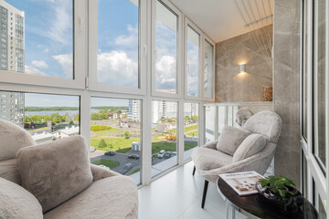 Glazed balcony interior with plush armchairs and panoramic view © валентин Орсик