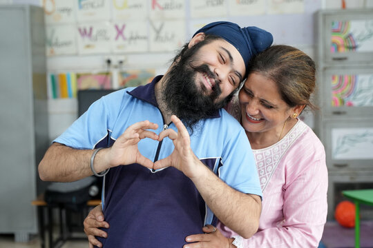 Indian special needs student expressing happiness and affection with a caring female teacher in an inclusive special education classroom.