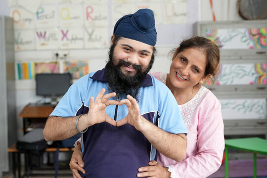 Indian special needs student expressing happiness and affection with a caring female teacher in an inclusive special education classroom.