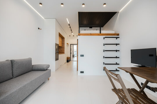 Raised mezzanine sleeping loft with black steel ladder in studio apartment
