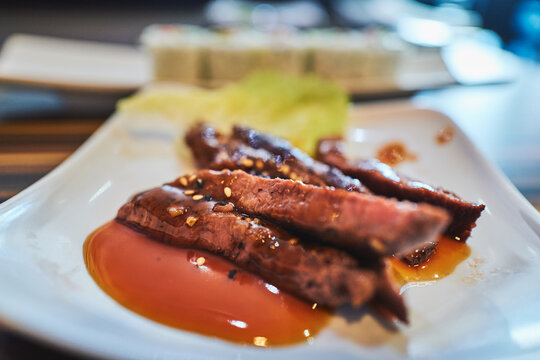 Close-up of beef tataki slices in a pool of teriyaki sauce