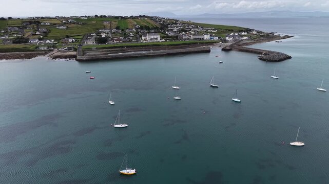 A beautiful top view of Irish harbour near Mullaghmore, County Sligo, Ireland. Aerial drone footage flying around the coastal village, showing a numerous sailing yachts anchored in calm blue waters in