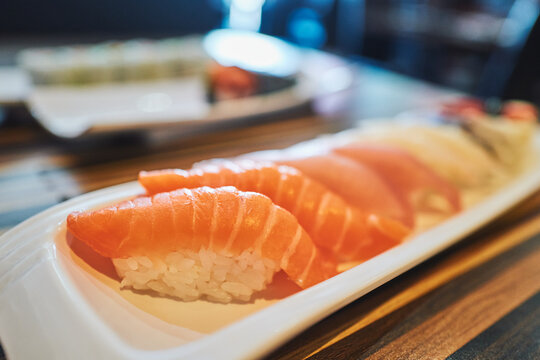 Salmon nigiri sushi from the side in moody restaurant light