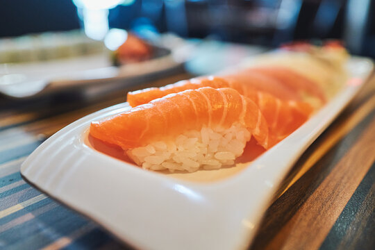 Salmon nigiri sushi on a white plate at a restaurant