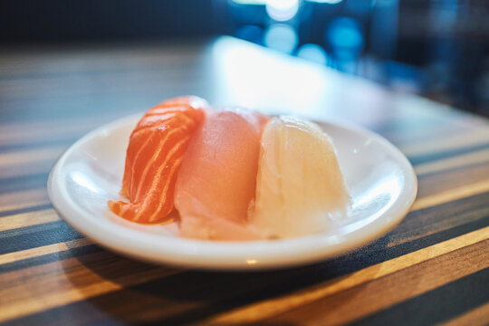 Three pieces of sashimi on a small round white plate
