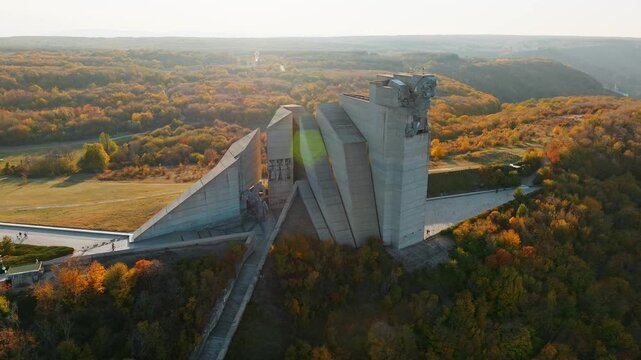 Monument Creators Bulgarian State Shumen plateau massive brutalist concrete monument autumn foliage landscape aerial drone view golden sunset light Bulgaria