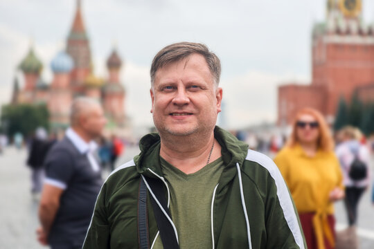 A blonde tourist stands in Red Square in Moscow enjoying sightseeing near famous monuments historical buildings.