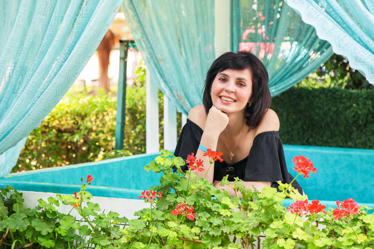 Portrait of attractive 40 year old brunette woman enjoying beautiful summer atmosphere outdoors, smiling happily on a warm sunny day.